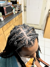 a person with dreadlocks sitting in a kitchen