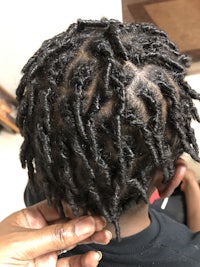 a woman getting her hair done with dreadlocks