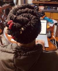 a person with dreadlocks sitting at a table with a laptop