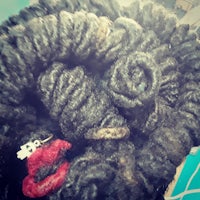 a close up of a black dreadlock with a red bow