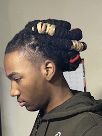 a young man with dreadlocks looking at his phone