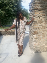 a woman leaning against a stone wall