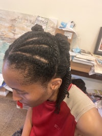 a woman is sitting in a chair with her hair in braids